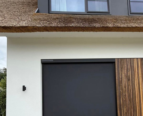 Close-up van het mat zwarte doek van een Heroal solar screen, passend bij de zwarte kozijnen en houten details van de woning.